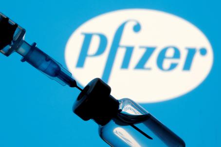 A vial and sryinge are seen in front of a displayed Pfizer logo in this illustration taken January 11, 2021. REUTERS/Dado Ruvic/Illustration